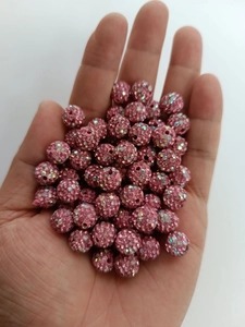 Macro view of a 10mm pink disco ball bead with rhinestones held in palm for scale