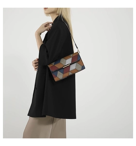Detailed close-up of a stylish geometric patchwork shoulder bag featuring metallic accents