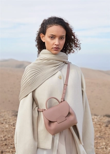 Close-up of a pink luxury leather handbag featuring a curved top handle and flap closure
