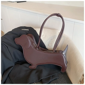 Detail view of the sleek dark coffee dachshund-shaped creative crossbody bag on a beige chair
