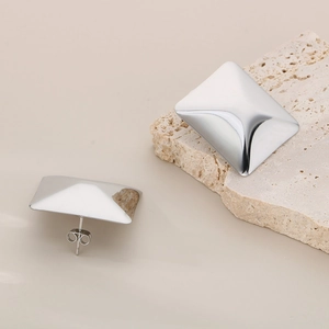 Polished silver square geometric stud earrings displayed on natural travertine stone