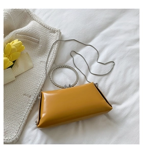 Detail of yellow leather bag with sparkling rhinestone ring handle and silver chain strap