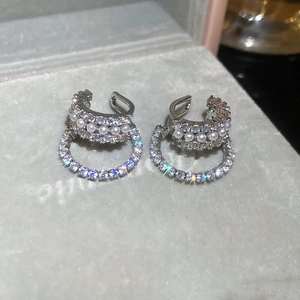Macro detail of silver ear cuffs featuring layered rows of white pearls and sparkling zircons