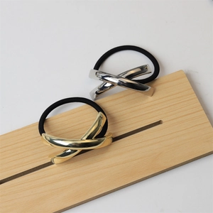 Macro detail of high-shine gold and silver X-shape metal accents on elastic hair bands