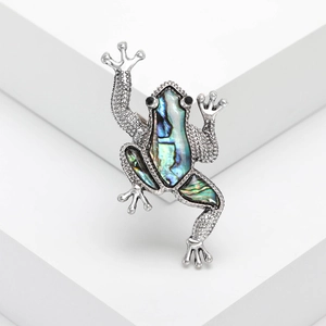 Vintage silver frog brooch with iridescent abalone shell on a white display stand