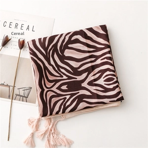 Flat lay of brown zebra print beach shawl with decorative tassels and a magazine