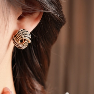 Gros plan de boucles d'oreilles dorées avec rayures noires et cristaux brillants