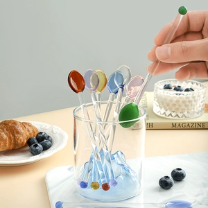 Set of 8 colorful heart-shaped glass stirring spoons for coffee and juice on a breakfast table
