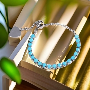 Detail of adjustable silver bracelet with turquoise stones and heart charm pendant