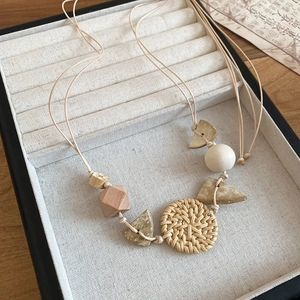 Close-up of geometric wood beads and handmade rattan pendant on a bohemian necklace