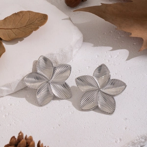 Detailed view of silver flower earrings with vintage texture on a stone platform