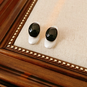 Close-up of black oval stud earrings on vintage linen display tray with silver backing