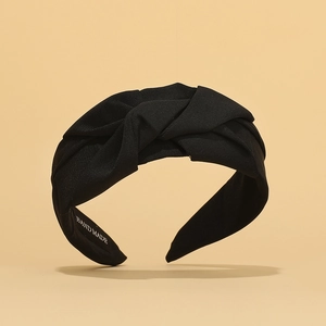 Detail of a black fabric twisted headband with Hand Made label on inner side