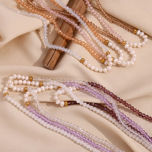 Detail of beaded necklace with freshwater pearls, crystals, and gold beads on satin