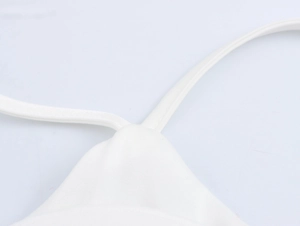 Detailed close-up of white floral camisole top with thin spaghetti straps and satin texture