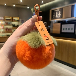 Macro shot of plush persimmon keychain with Good Luck tag and orange metal clasp