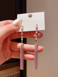 Detail of elegant gold chain tassel earrings with purple and pink crystal accents