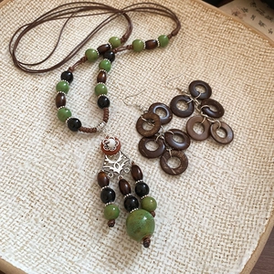 Detail view of vintage jewelry set with green ceramic beads and brown wooden rings on a tray