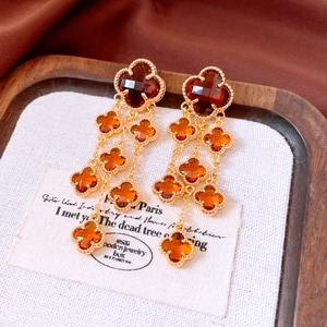 Detail of 18k gold plated long fringe earrings with amber glass clover charms and tassels