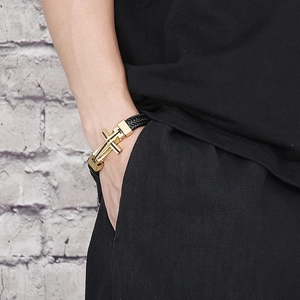 Men's black braided leather bracelet with golden cross clasp shown on a model