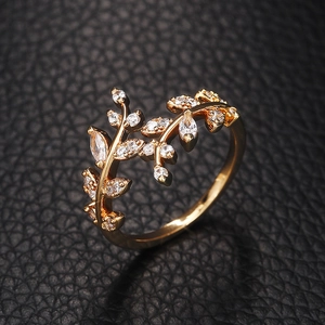 Detailed close-up of a gold leaf ring with sparkling clear stones on black leather