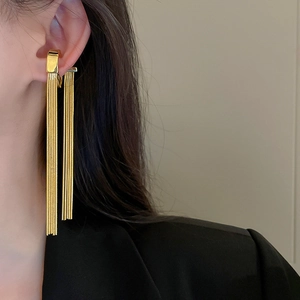 Close-up of golden metal tassel ear cuff worn by a model in black suit for modern style