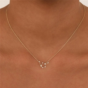 Detailed view of gold Virgo zodiac pendant necklace with white zircon on a female neck