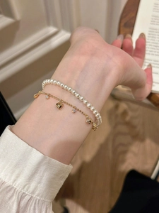 Detail of double-layer heart bracelet with white faux pearls and golden star charms
