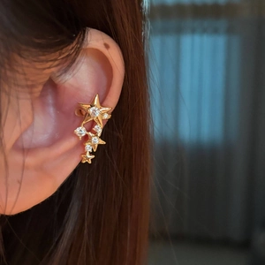 Detailed view of a gold star ear cuff with sparkling zircons on a model's ear