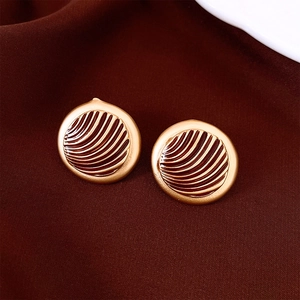 Close-up of vintage round gold earrings with dark red enamel on silk background