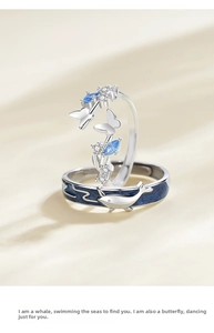 Detail view of whale and butterfly couple rings on cream silk with blue enamel and crystals