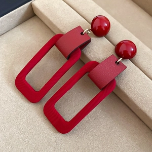 Detailed close-up of dark red rectangular earrings with flocked leather texture details