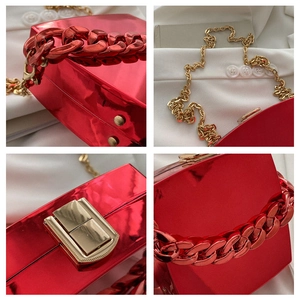 Detail of red glossy hard shell evening bag with red chain handle and gold shoulder strap