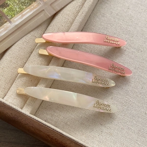 Detail of pink and pearlescent white French hair clips on linen jewelry tray