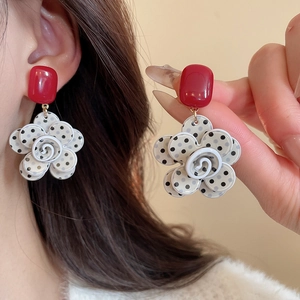 Detailed view of red square stud and white polka dot flower earring with gold link