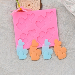 Stampo in silicone a cuore rosa con creazioni in resina sfumata su fondo grigio