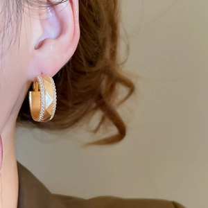 Dettaglio di orecchini a cerchio in oro 18k con sfaccettature geometriche e zirconi