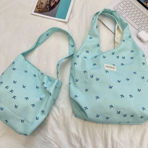 Detail showing two light blue canvas bags with dark blue swallow print and fabric labels