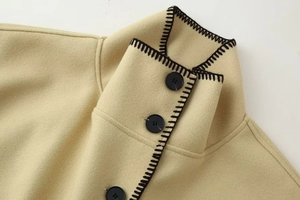 Detailed close-up of high turtleneck collar with black buttons and embroidery on wool coat