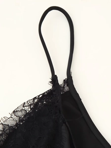 Detail der zarten schwarzen Spitzennähte und dünnen Träger am Satin-Unterkleid