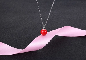 Detail showing the S925 silver hallmark on a red pearl pendant over a pink silk ribbon