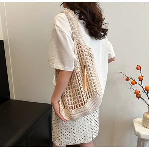 Detail of beige hand-woven crochet tote bag with mesh pattern and fringe decoration