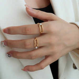 Modern geometric gold plated ring with faux pearl detail worn on finger by a model
