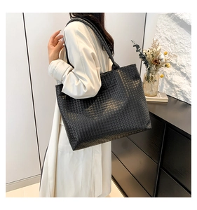 Detail of the black woven leather texture and large capacity on a slouchy shoulder bag
