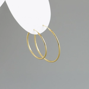Detailed view of polished gold hoop earrings featuring a classic minimalist tubular design