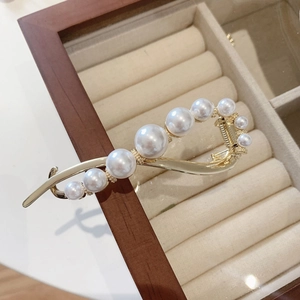 Elegant gold hair clip with gradient white pearls displayed in a velvet jewelry box