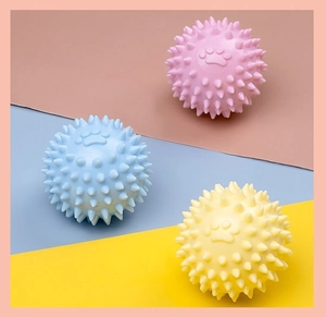 Vue détaillée de trois balles de massage à pointes pour animaux en rose, bleu et jaune