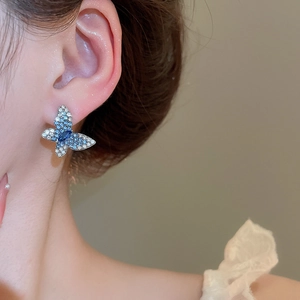 Détail des boucles d'oreilles papillon avec strass bleus dégradés et aiguille en argent