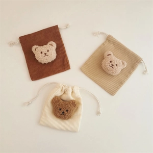 Three bear-themed corduroy drawstring pouches in brown, beige and white colors