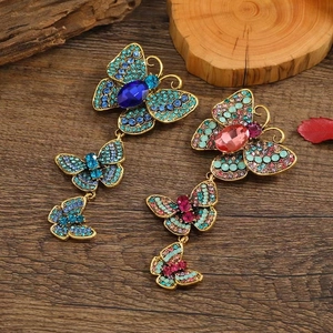 Vintage butterfly tassel earrings with colorful rhinestones on a dark wood surface